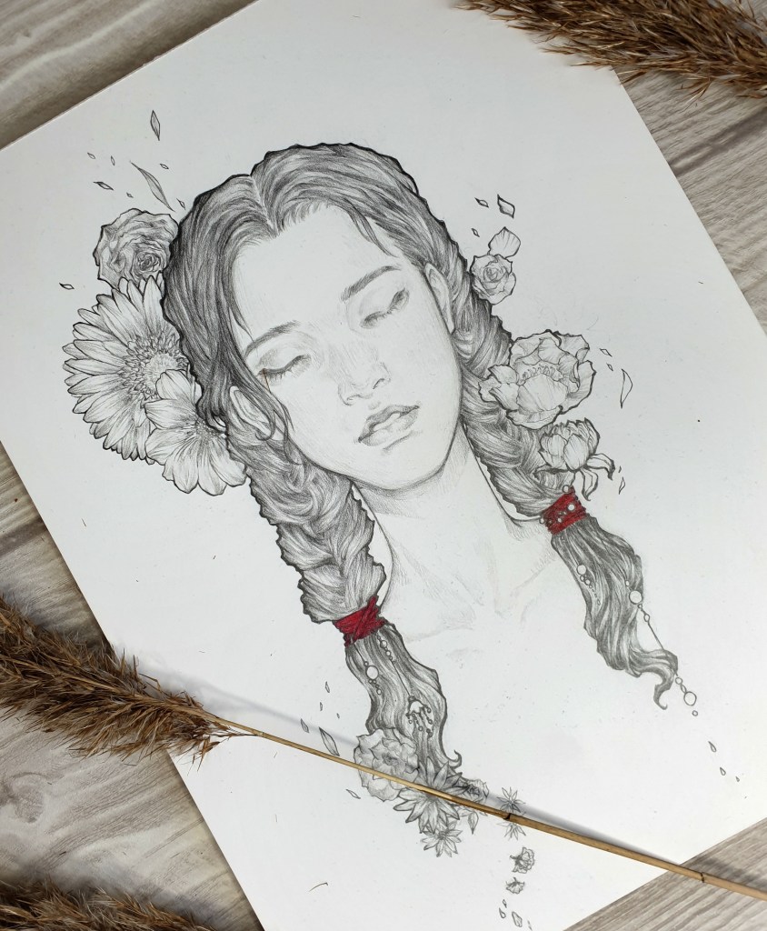 A flatlay photo of a pencil drawing on Bristol card. Three pampas stalks frame the drawing of a young woman with closed eyes and a subtle smile.